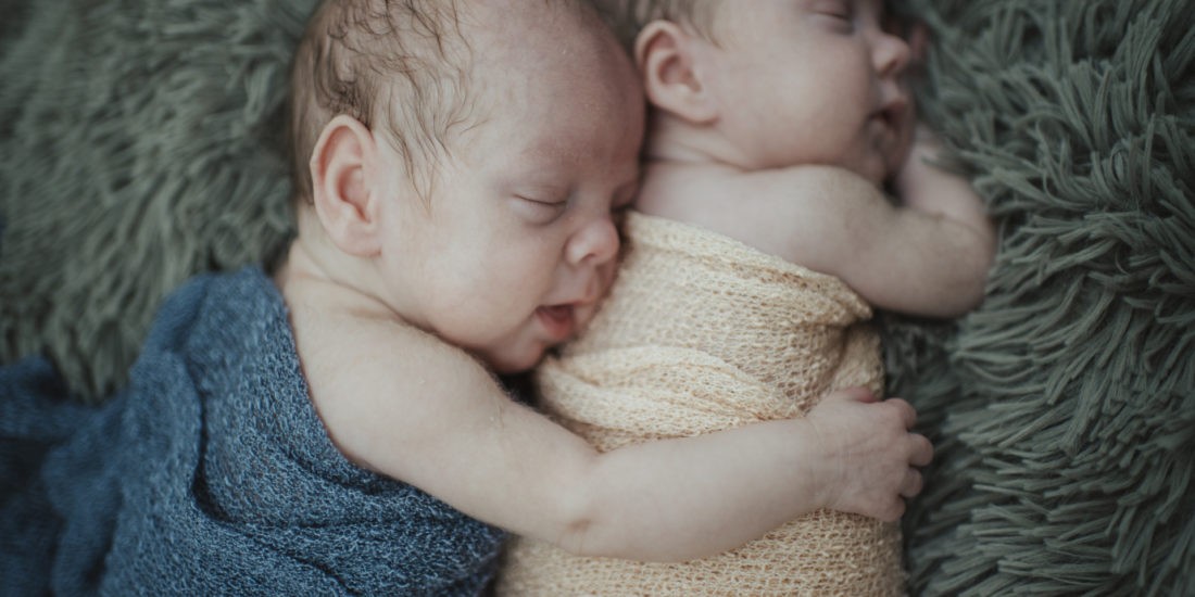 Babyshooting mit Zwillingen, bei dem ein Zwilling einen anderen umarmt und einmalige Babyfotos entstehen – Verena Schick Fotografie